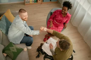 Young man warmly greeting a man in a wheelchair while others smile during an inclusive group gathering, digital marketing agency in philadelphia