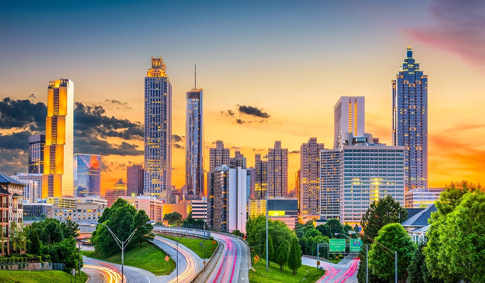 Urban cityscape at sunset with skyscrapers, highway, and warm golden sky