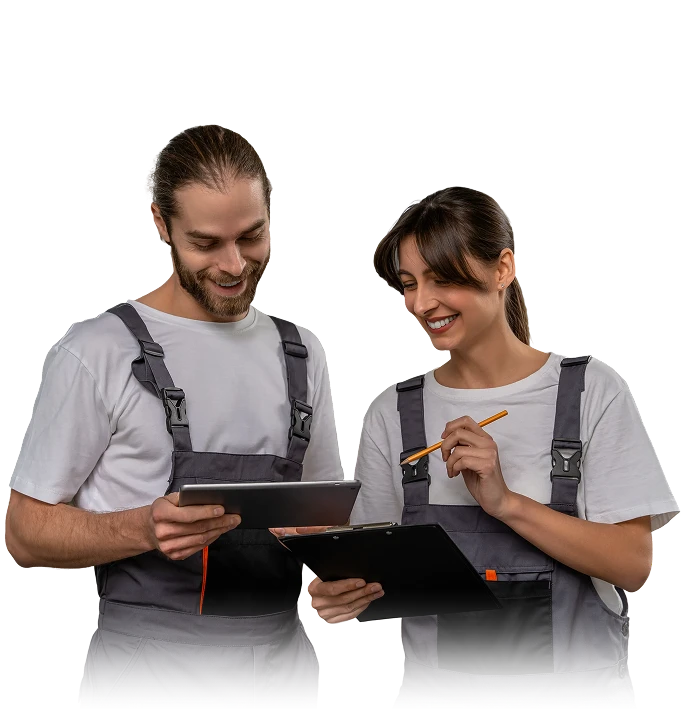 Two technicians in work overalls reviewing a checklist on a tablet and clipboard