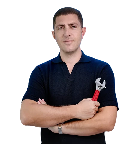 Denis holding a wrench and smiling at the camera