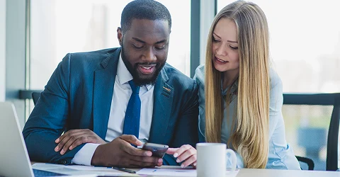 Business colleagues reviewing information on a smartphone in a modern office.