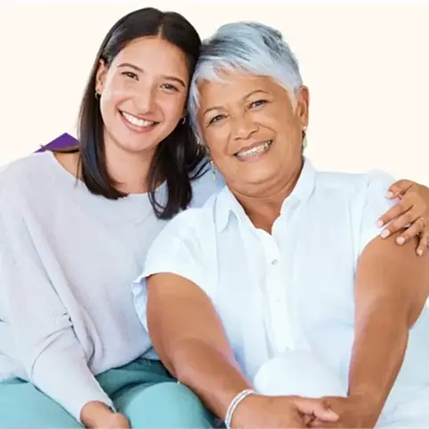 Young woman and older woman smiling together against a light background