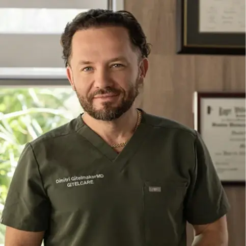 Portrait of Dr. Dimitri Gitelmaker MD in olive green scrubs in a medical office setting