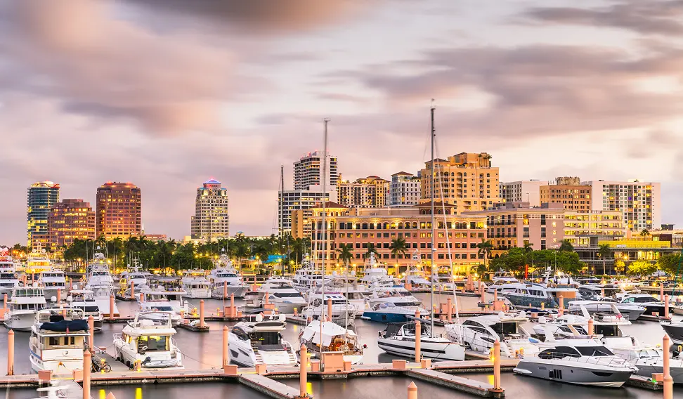 West Palm Beach waterfront skyline with luxury yachts moored at a marina at dusk